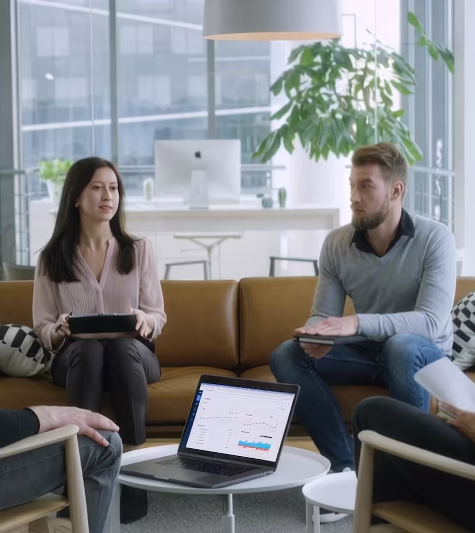 Customers having a discussion around a laptop showing a ChartMogul dashboard.